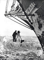 Frank Hurley with movie camera beneath the bow of the Endurance