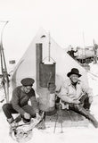 Ernest Shackleton and Frank Hurley (skinning penguin) at Patience Camp