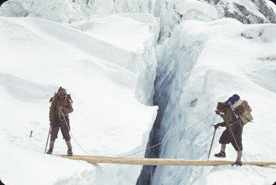 Sherpas wearing crampons crossing log bridge