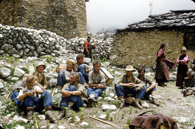 Team members resting on rocks in a Nepali village