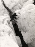 A Sherpa crossing a crevasse on a ladder between Camps II and III