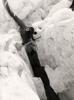 A Sherpa crossing a crevasse on a ladder between Camps II and III